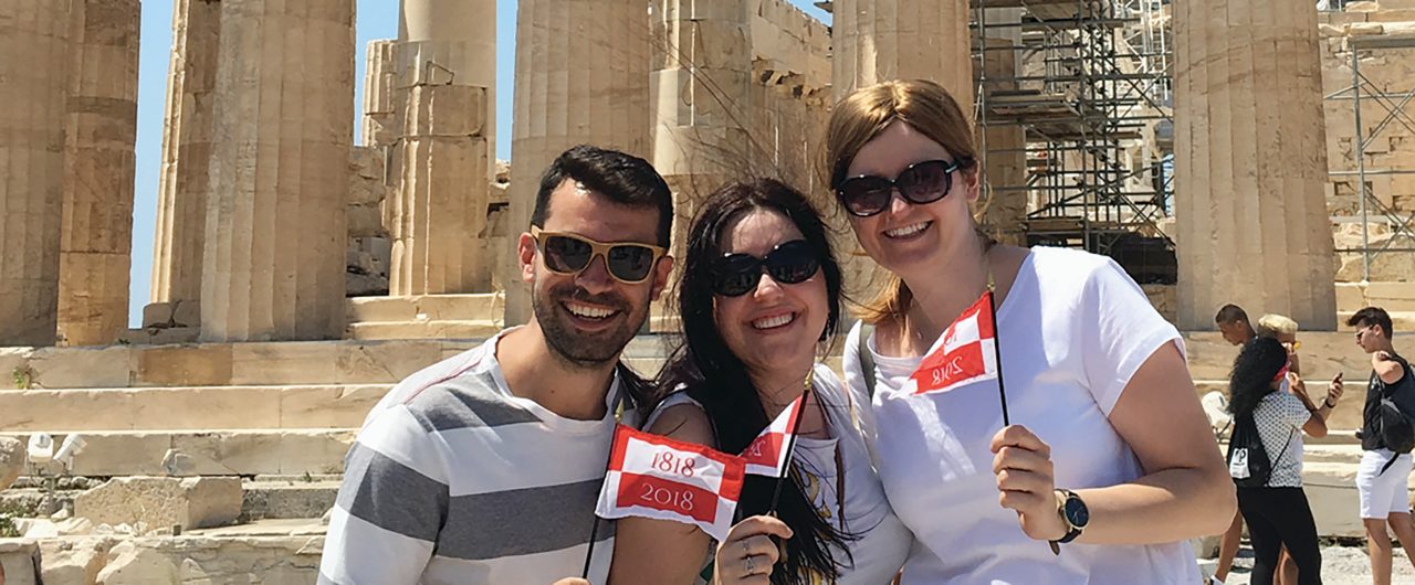 BBH employees at Acropolis holding BBH flags-Banner