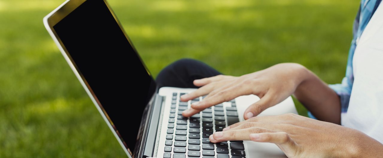 Closeup of black female hands working on laptop with blanck screen for copy space; remote working concept