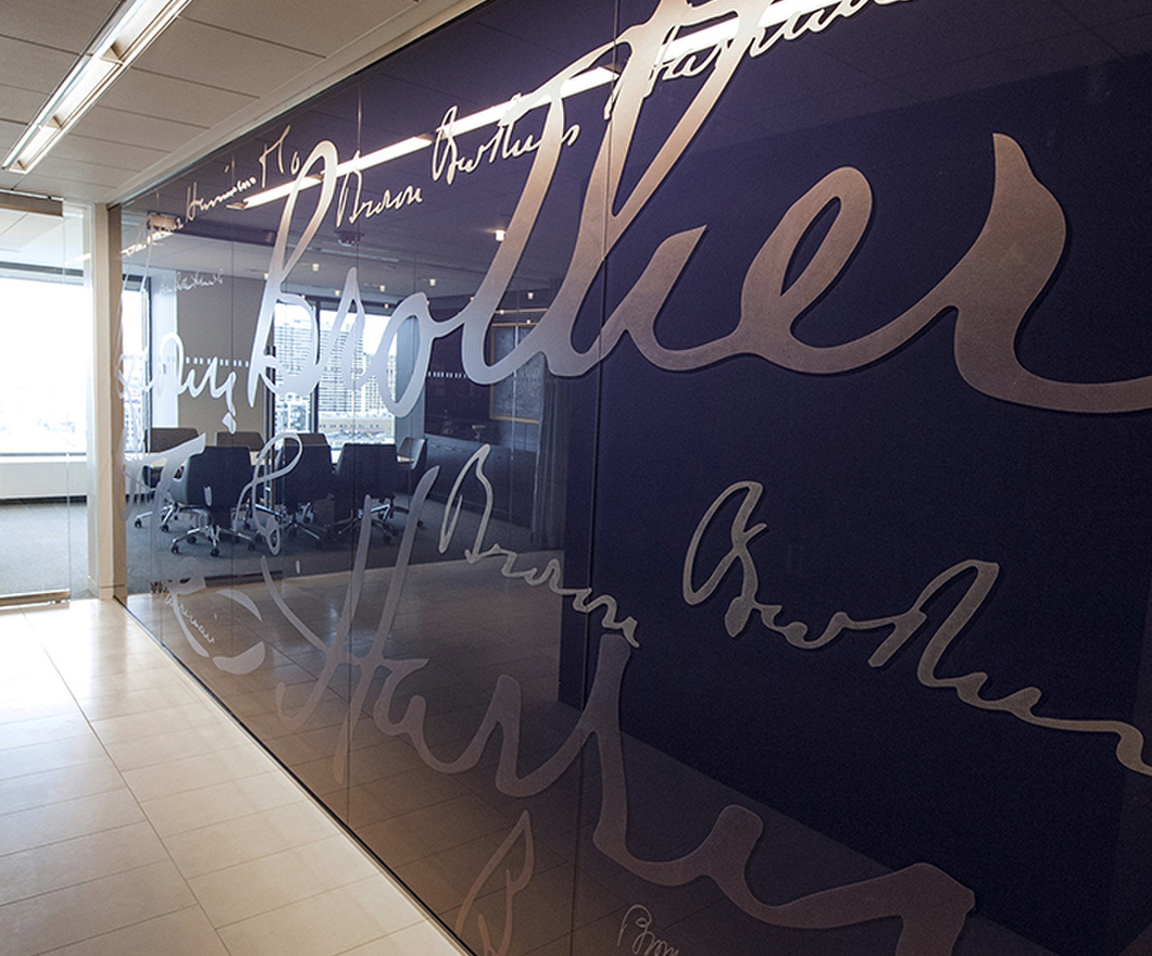 large cursive silver writing on a purple right wall in a hallway with a tiled floor and overhead ceiling light