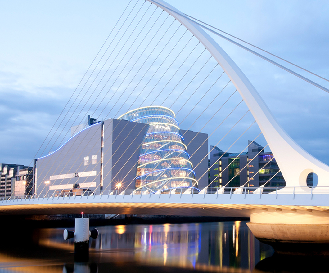 Samuel Beckett Bridge in Dublin after sunset. Modern bridge with modern buildings and skyscrapers in the backround.