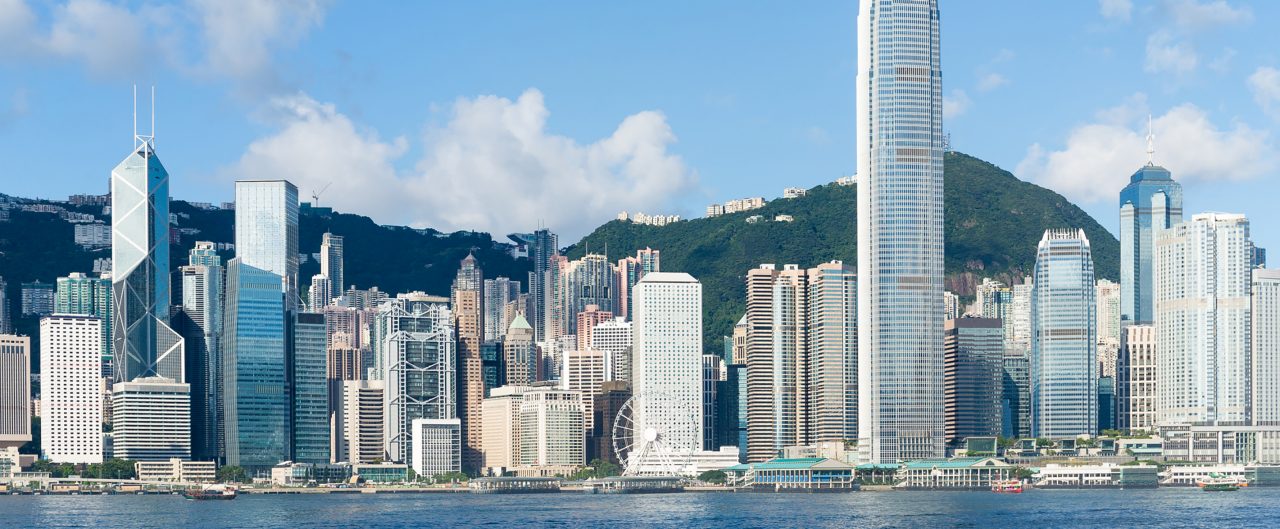 Hong Kong view from Victoria Harbour on sunny day with green mountains in the background