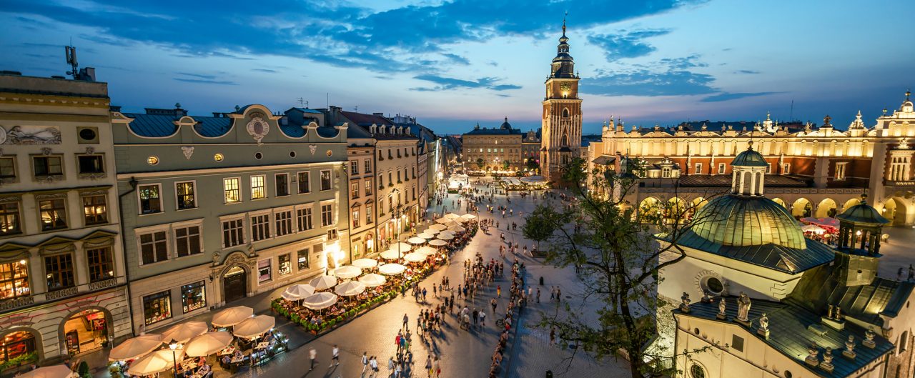 The market square in Krakow at sunset with people walking around 