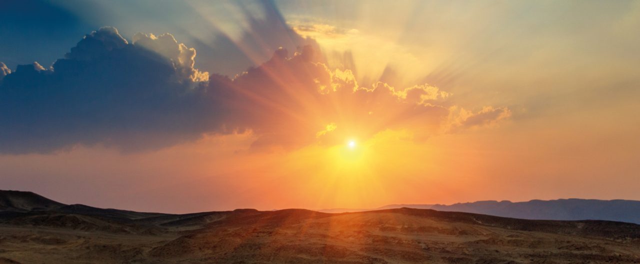 Landscape of beautiful sunset in the desert. View of high sandstone hills and dramatic cloudy sky