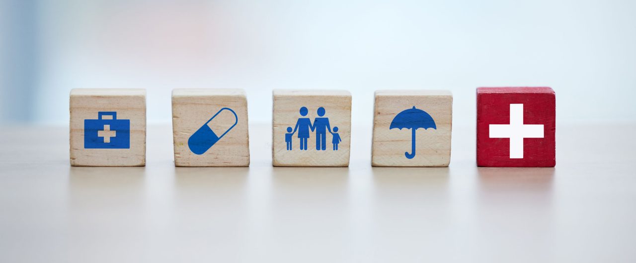 Healthcare, insurance and wooden blocks in studio on an empty gray background for safety or security. Abstract, medicine and health with block toys in a hospital or clinic for medical care