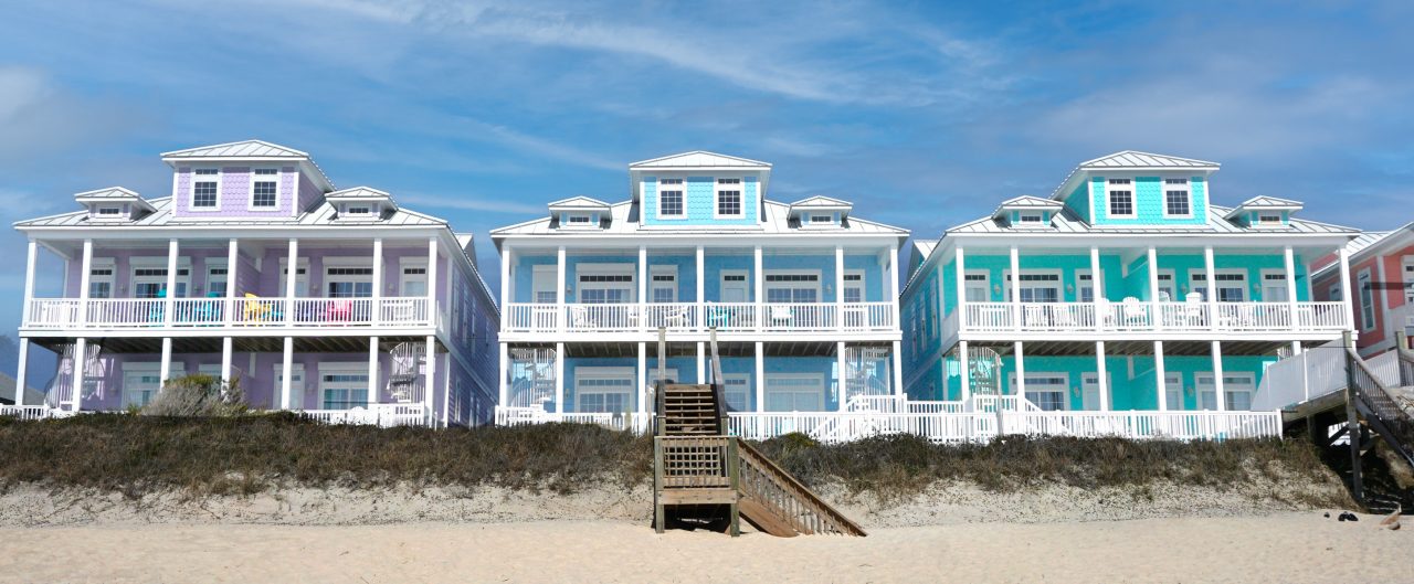 Colorful beach houses on a sandy beach under a blue sky on the North Carolina coast