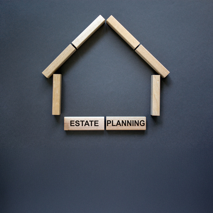 Model of a wooden house from wooden blocks. Words 'estate planning'. Copy space. Business concept. Beautiful grey background.