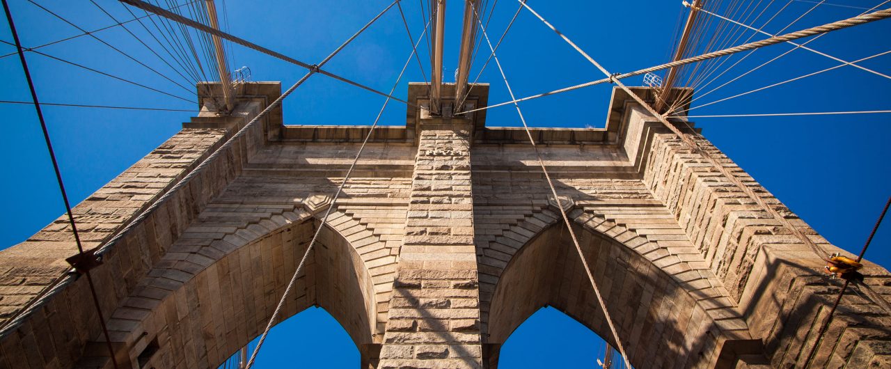 Upward View of the Brooklyn Bridge Against Bright Blue Sky