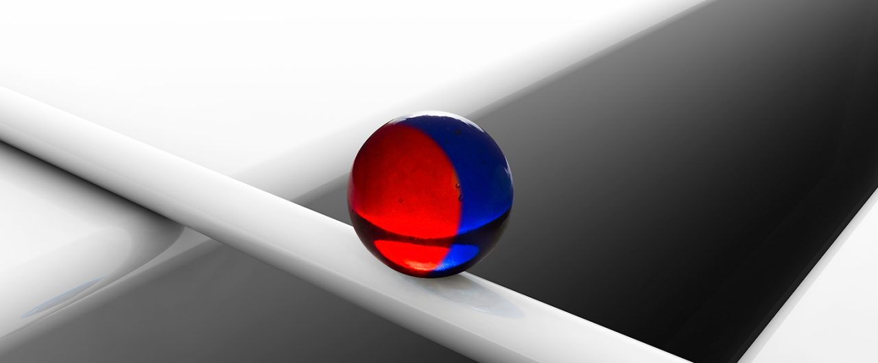 Blue red marble balancing on white cylinder 