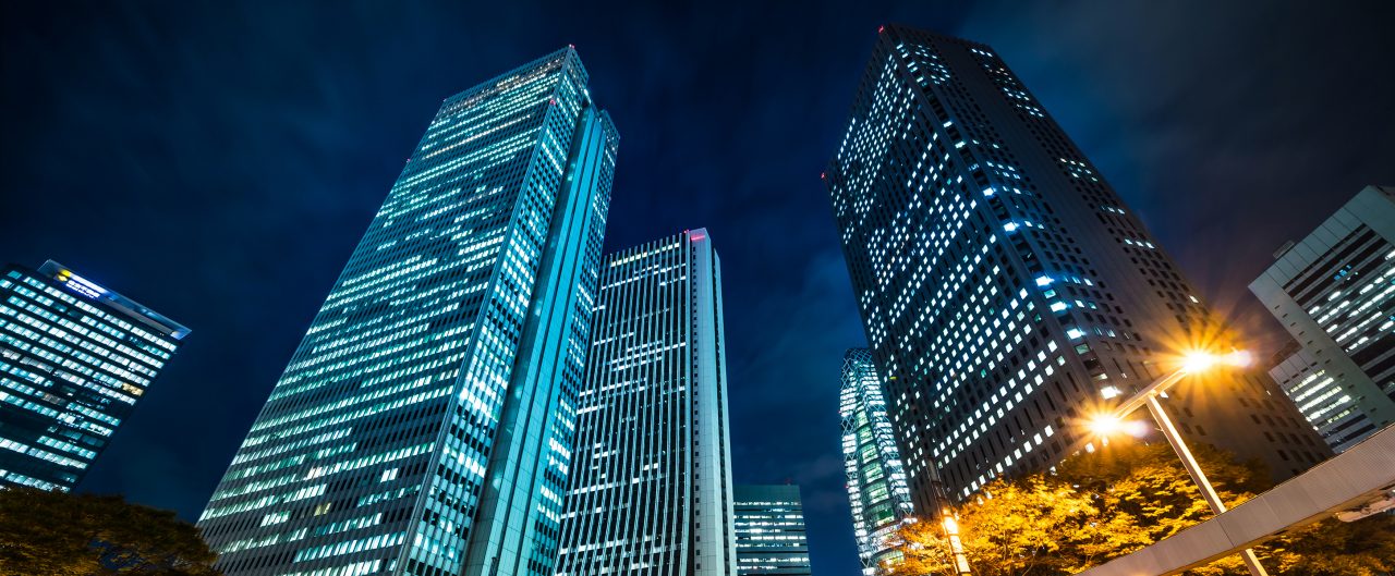 Looking up night view in road intersection of shinjuku, the silhouettes of skyscrapers reflect twilight sky in Tokyo, Japan