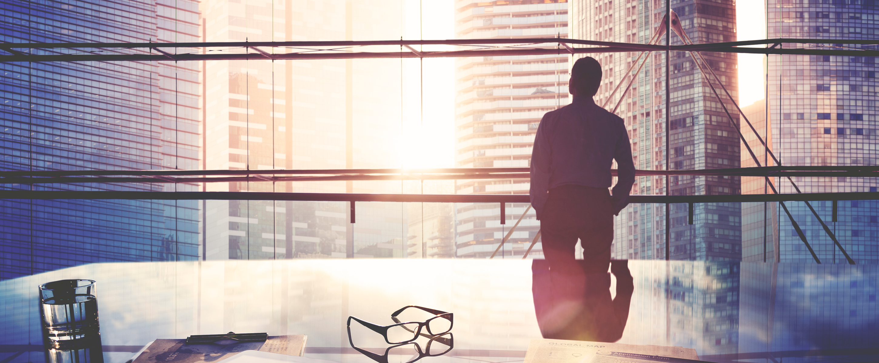 A man in an office looking out of the window at other skyscrapers 