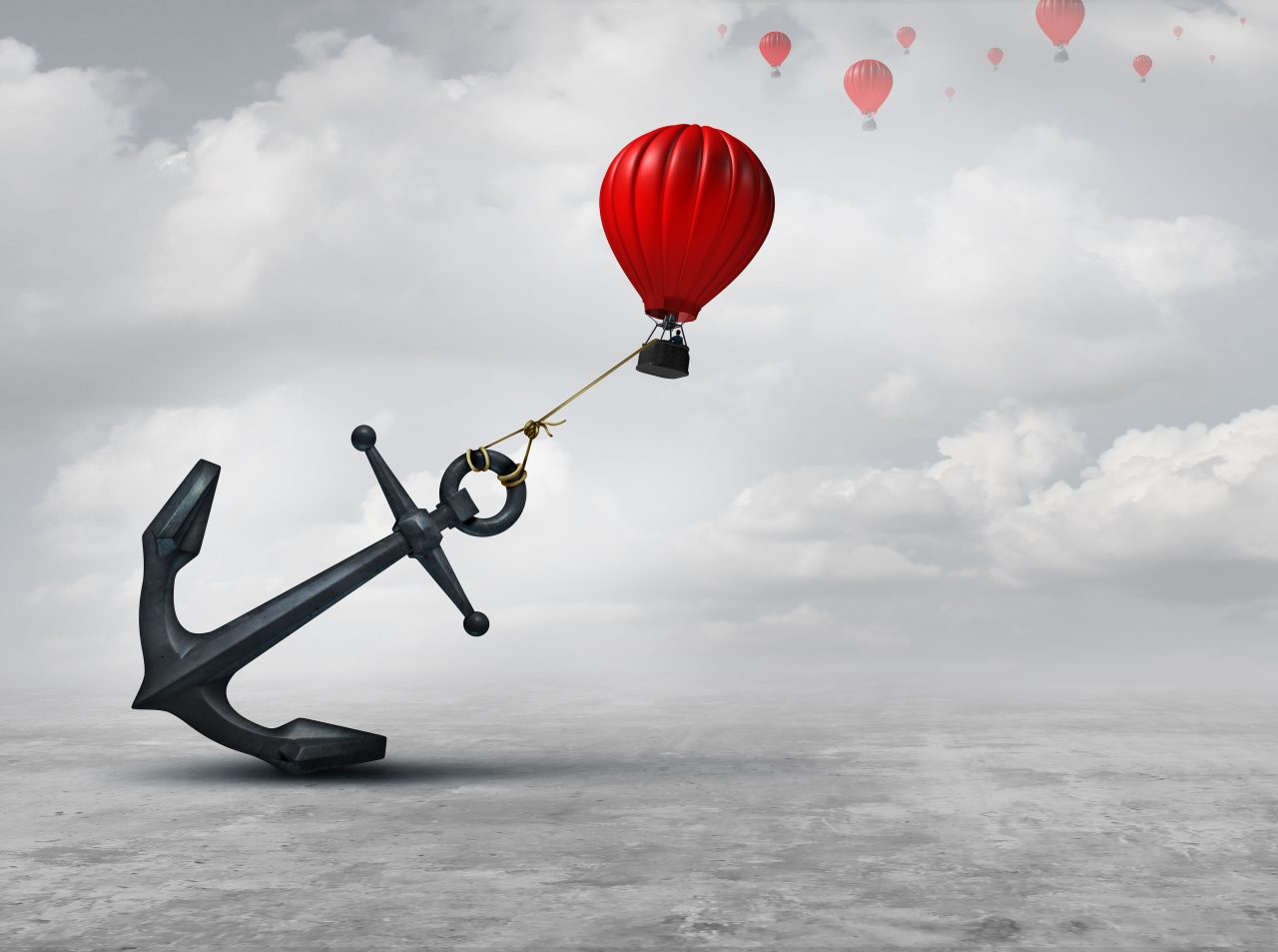 Hot air balloon attached to a big anchor with other balloons far off in the distant sky 