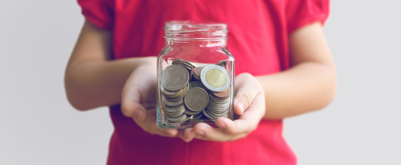 a child in a red shirt holding a jar of coins