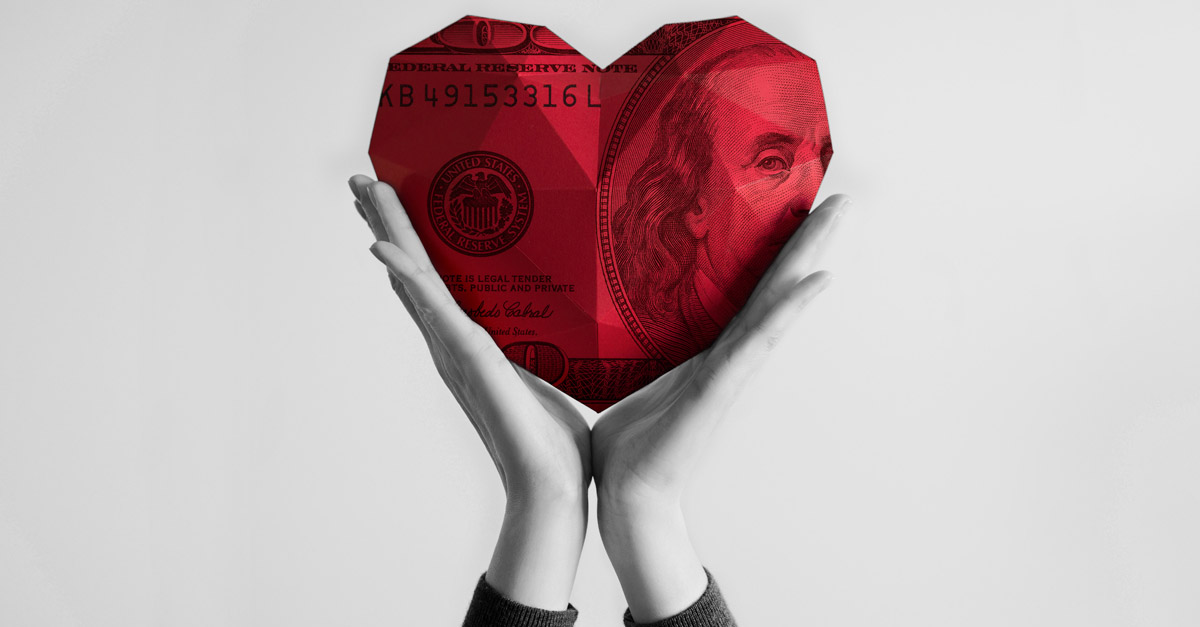 Giant red heart of money held by hands