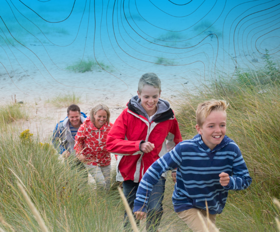Family of four running up the beach