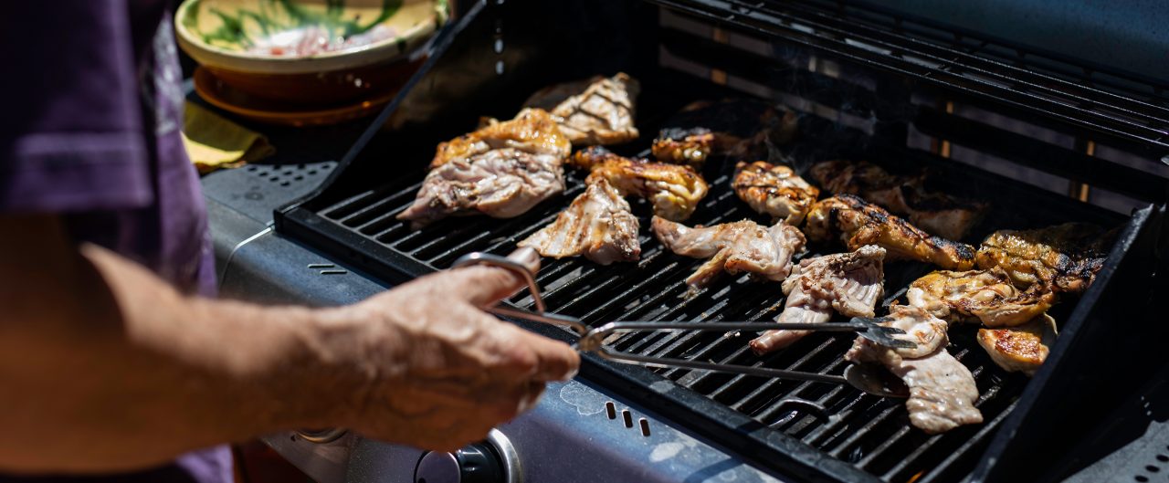 man preparing meat on barbeque