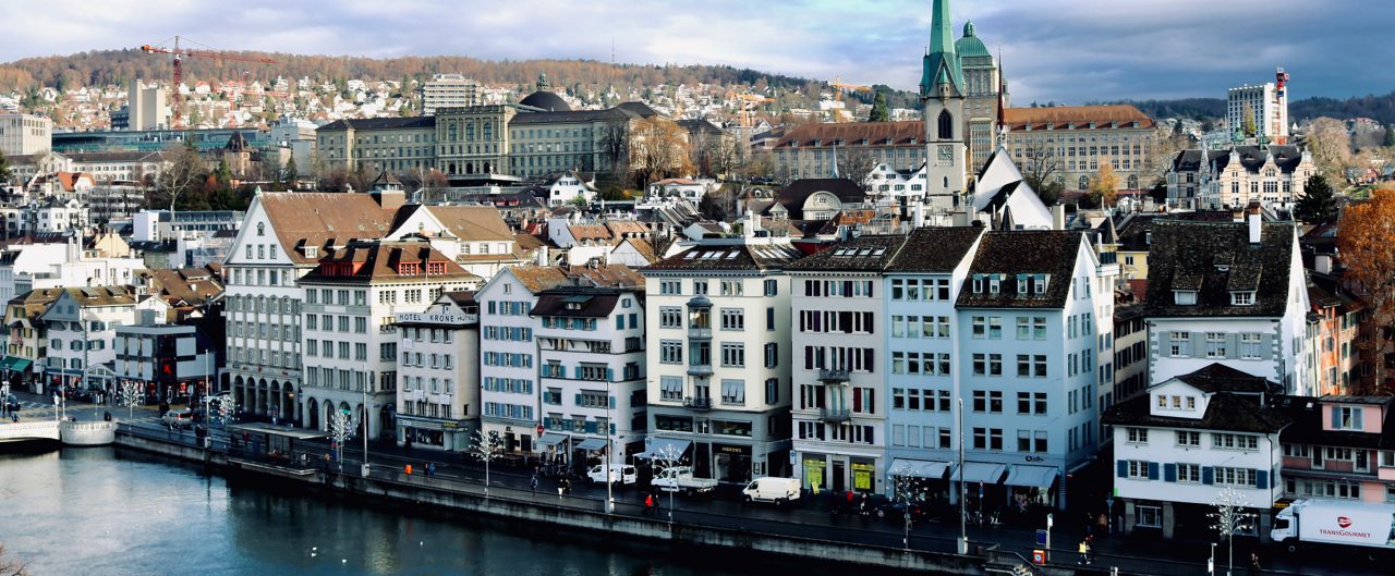 Zurich skyline with houses, churches, still water.