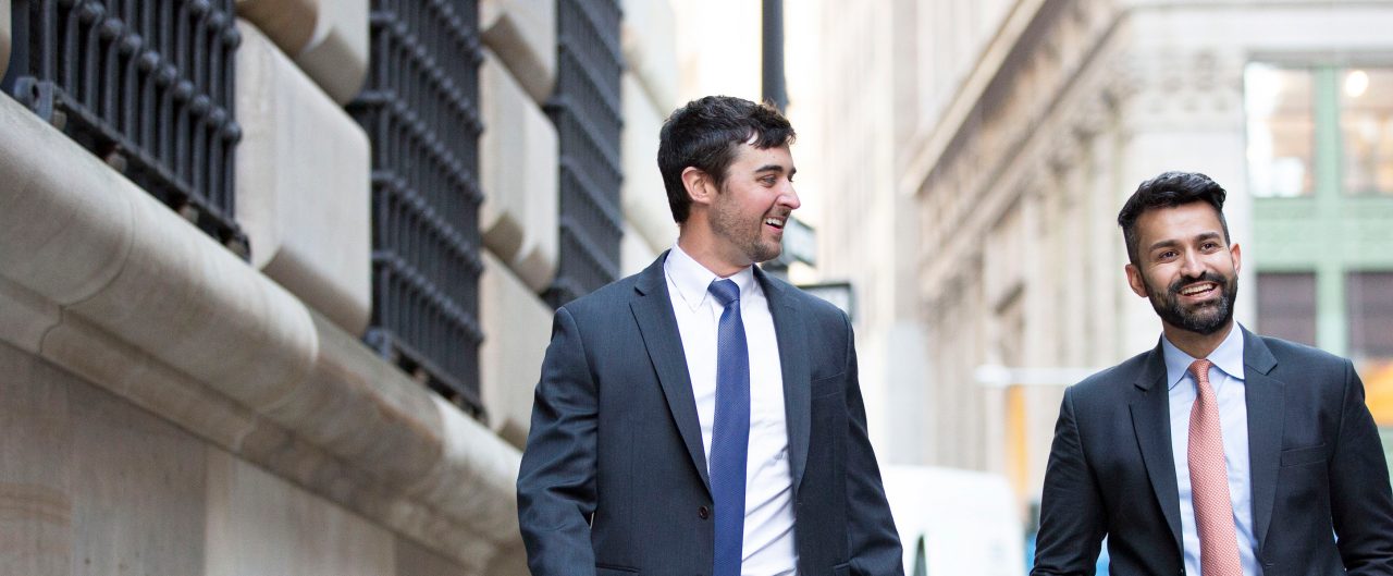 Two male BBH'ers walking side by side down a New York City street having a conversation