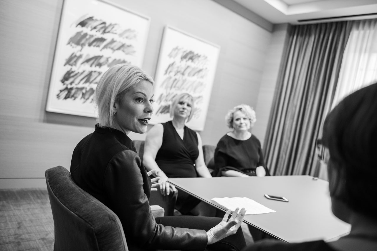 4 women speaking to each other around a square table 