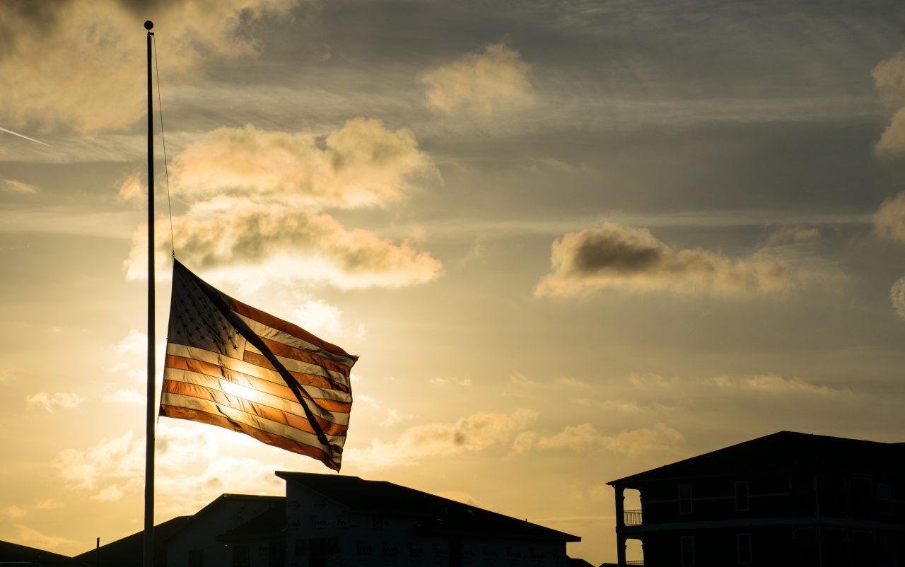 American flag at half mast during golden sunset 