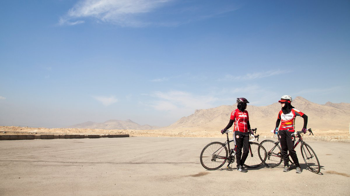 Two cyclists stand next to their bikes in the middle of a desert