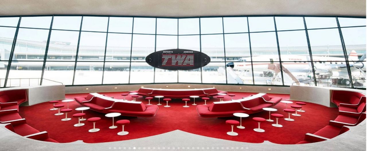 TWA conference room with a red carpet and red upholstered couches and chairs with a big window overlooking an airport