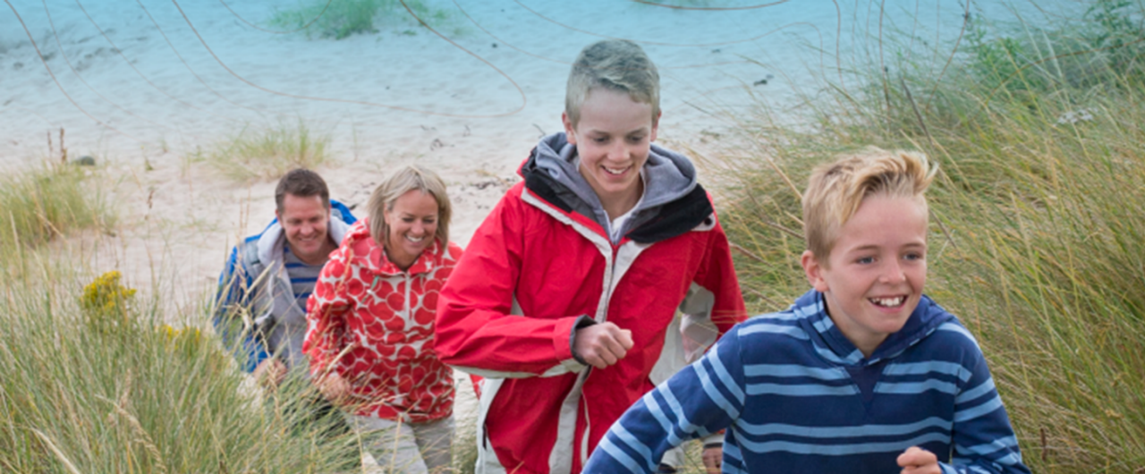 Family of four running up the beach 
