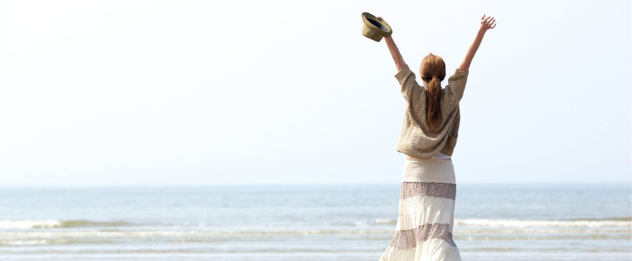 Woman with raised arms at the beach