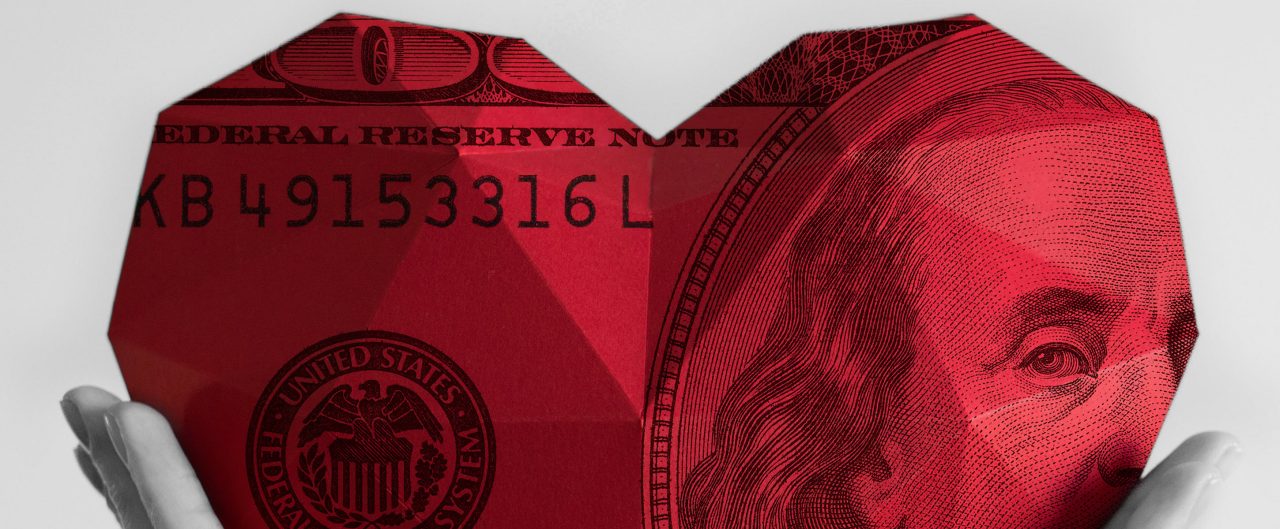 Giant red heart of money held by hands