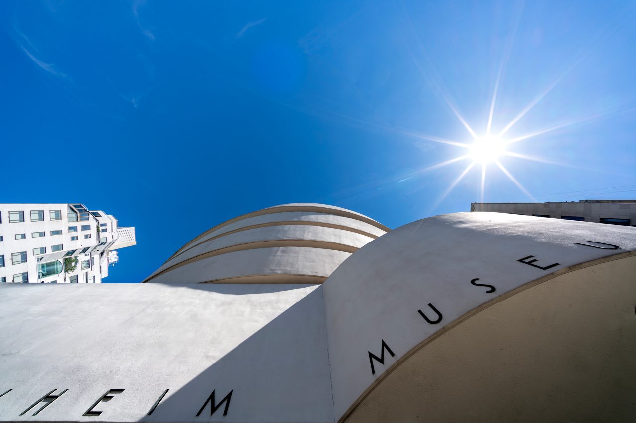 Close-up of the Guggenheim Museum title with a clear blue sky and shining sun