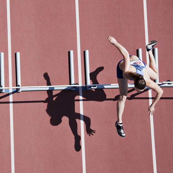 Female runner jumping over an obstacle on the track 