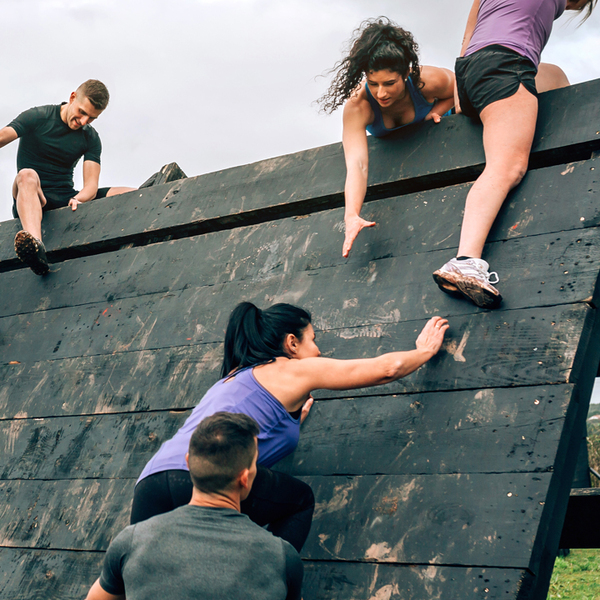 Group of participants in an obstacle course climbing a pyramid obstacle