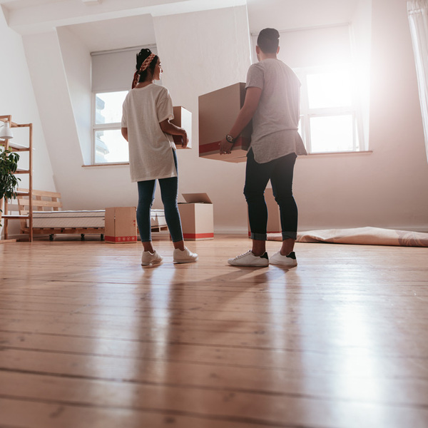 Young man and woman holding boxes and moving in new house.