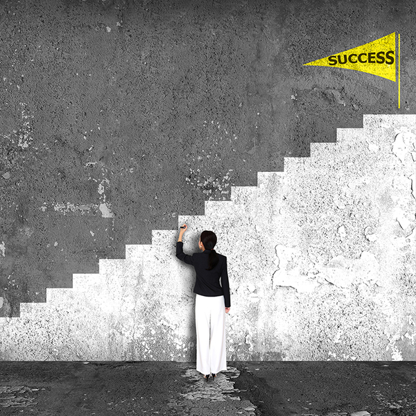 A woman drawing on a wall. The wall shows a staircase leading to success 