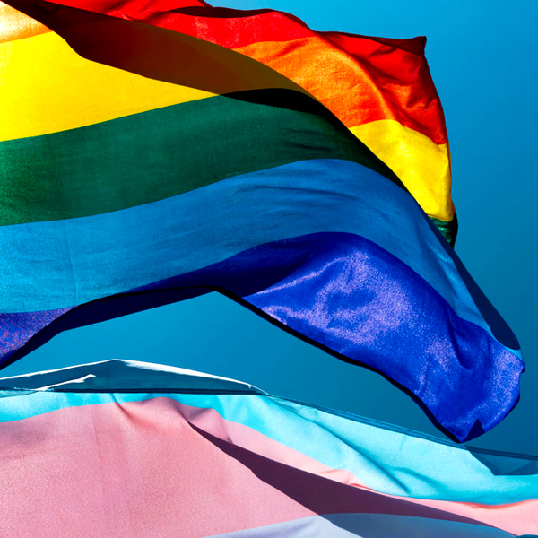 LGBTQ+ and transgender pride flag waving on the blue sky
