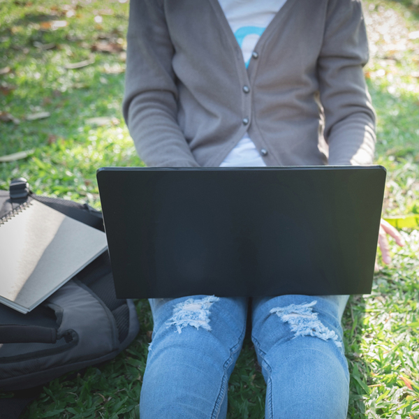 Laptop on the lap of a woman sitting on the lawn
