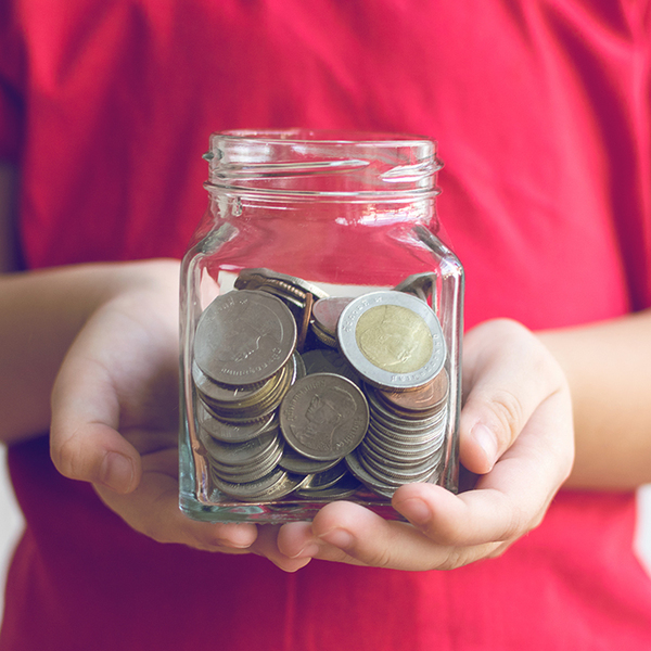 a child in a red shirt holding a jar of coins