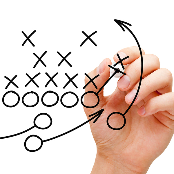 Hand of coach drawing American football strategy with black marker on white background