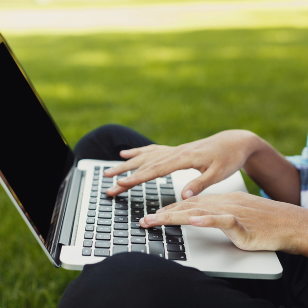 Closeup of black female hands working on laptop with blanck screen for copy space; remote working concept