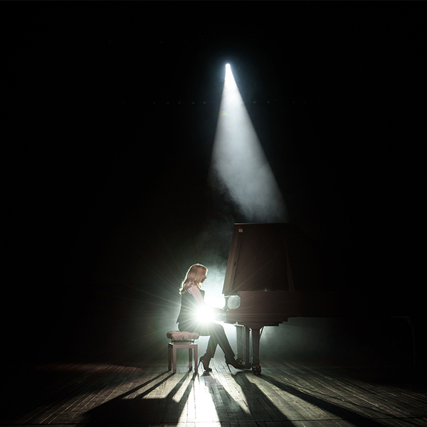 Close up view of a girl plays piano in a dark concert hall 