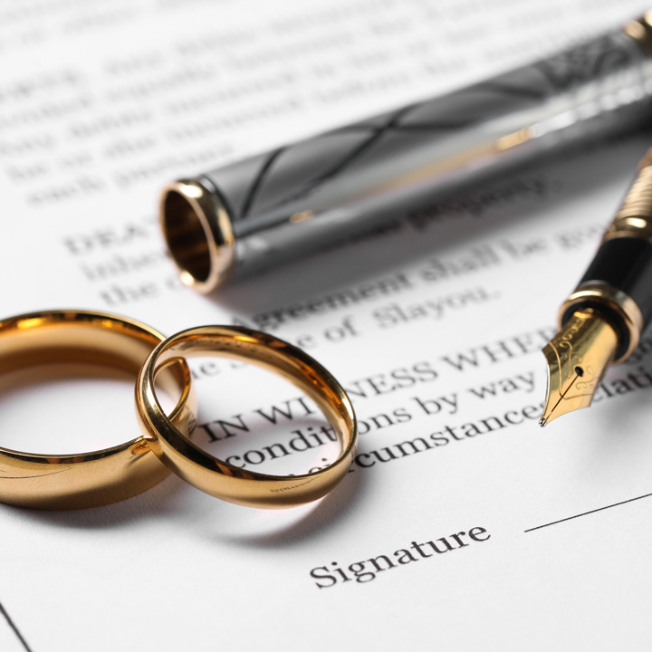 Marriage contracts, gold rings and pen on light wooden table, closeup