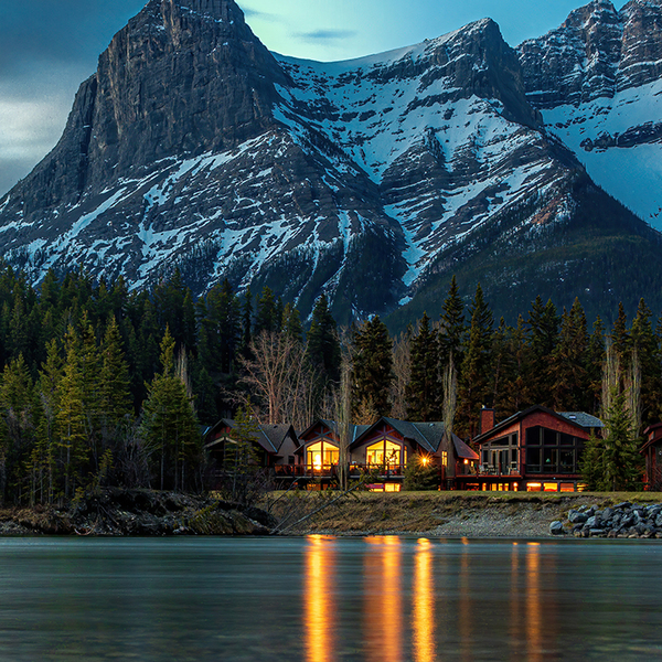 Wooden cabins in forest below mountain peak during night