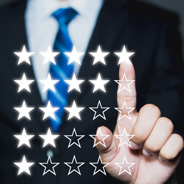 floating five stars (5) rating symbols in front of a businessman. The business man holding up his hand to select which rating he wants to pick.