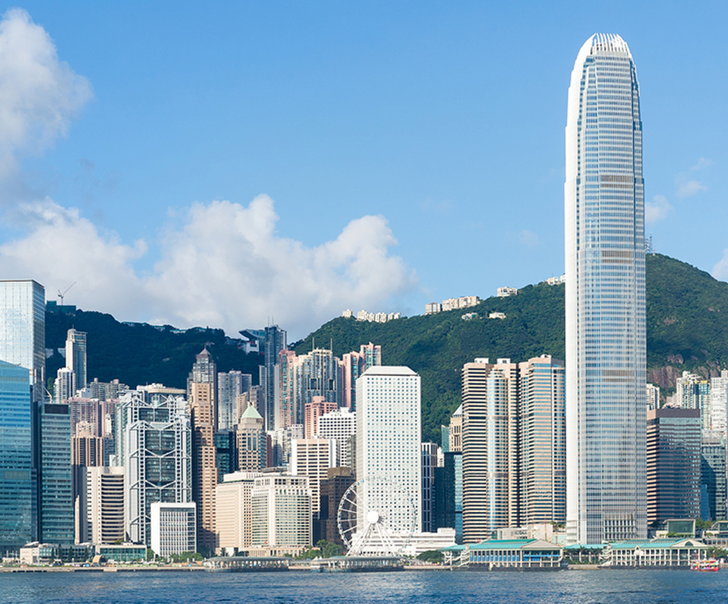 Hong Kong view from Victoria Harbour on sunny day with green mountains in the background