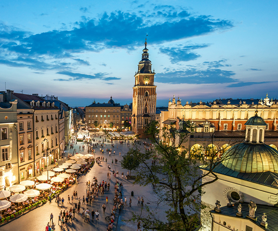 A view of the market square in Krakow at sunset with people walking around 