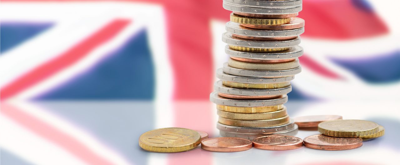 Coins stacked with United kingdom flag in background