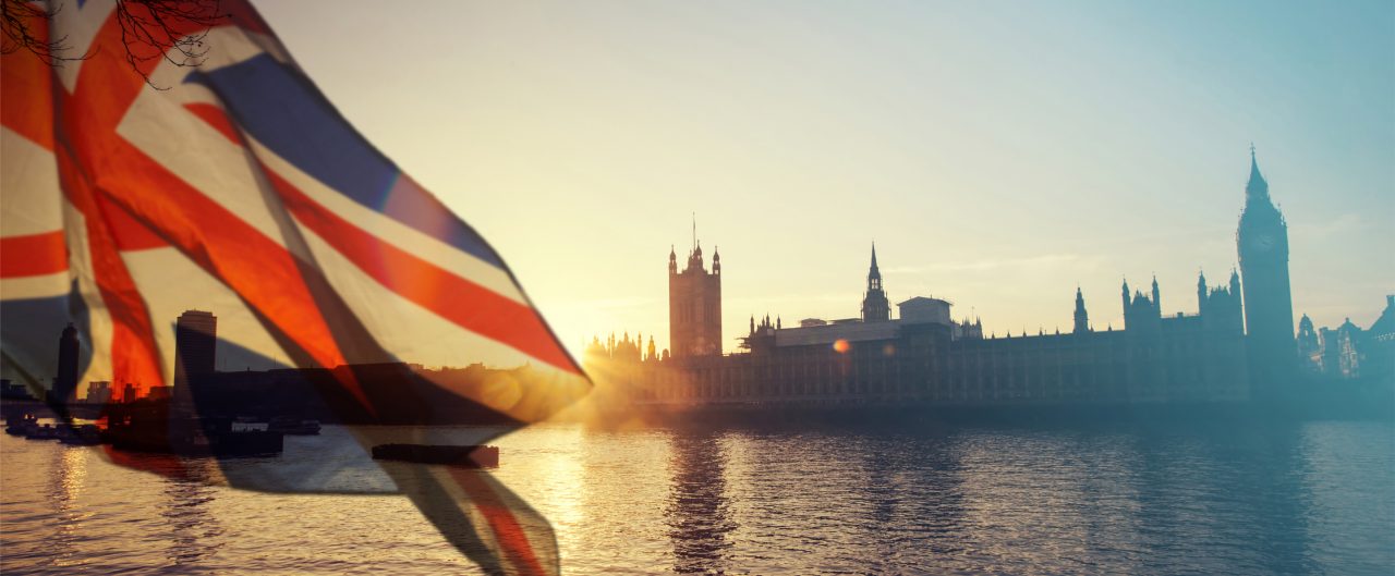 Union Jack flag flying in wind with London behind it