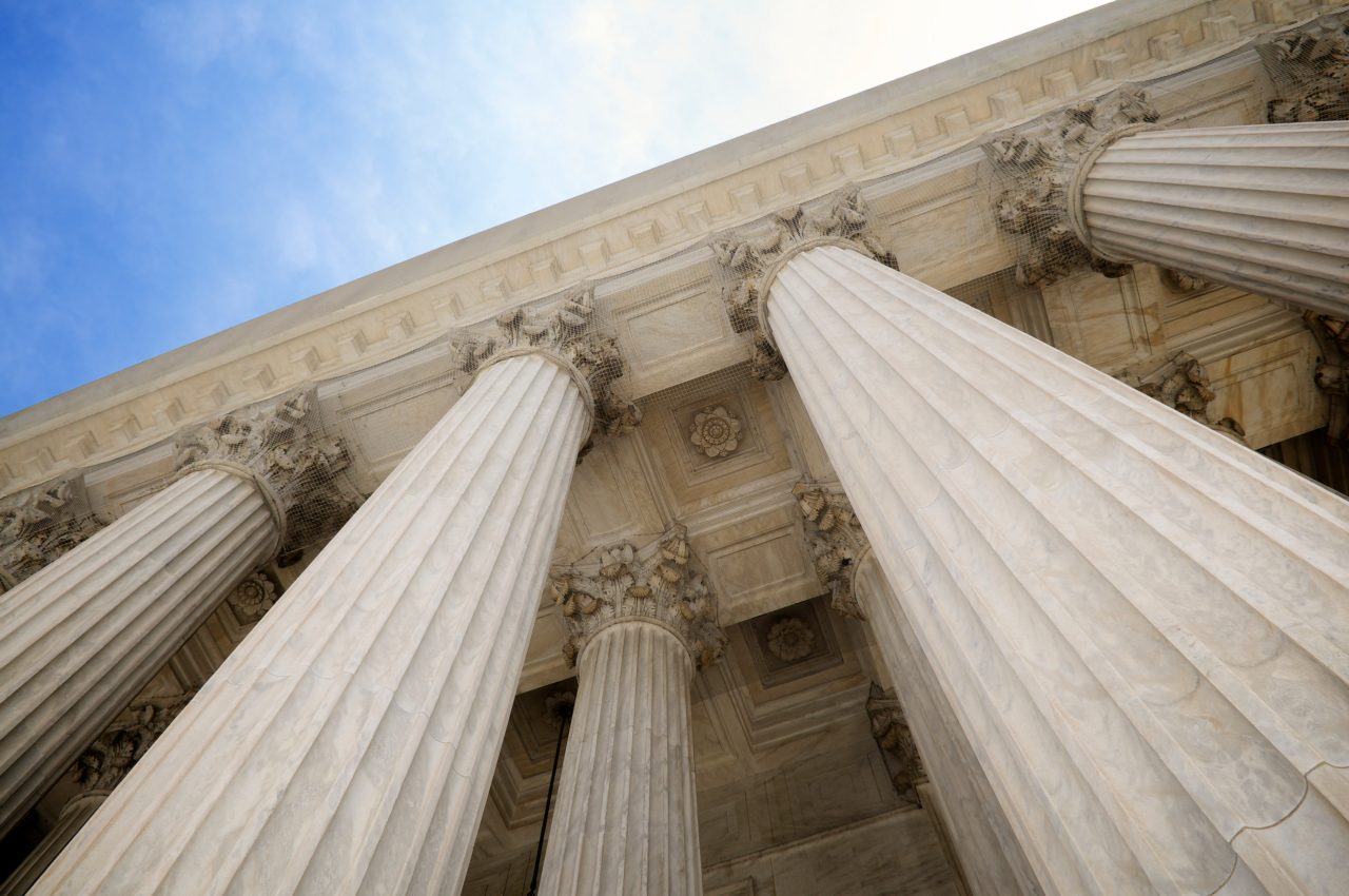 Upward View of Classical Stone Columns Against a Blue Sky