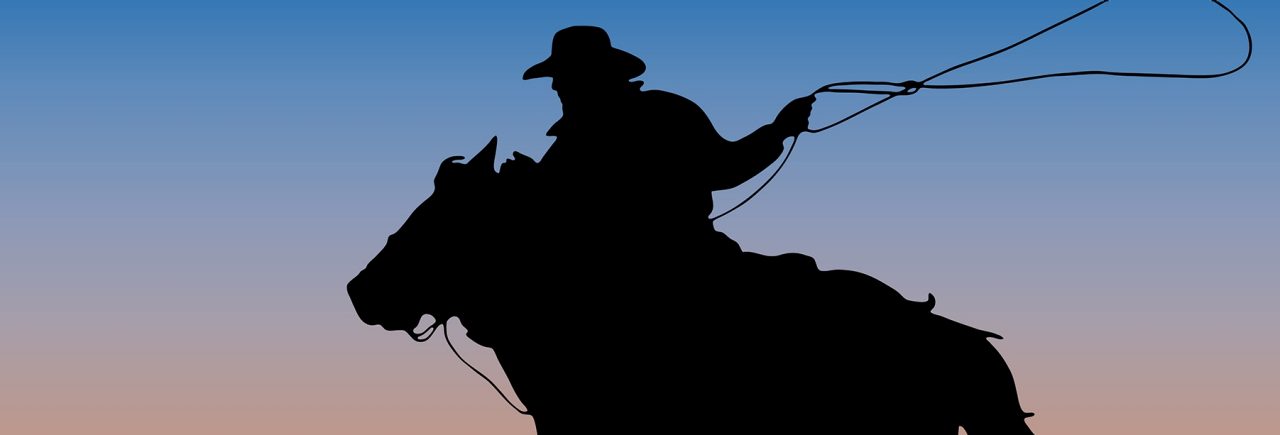 Silhouette of a cowboy on a horse with a lasso in front of a blue and orange sunset