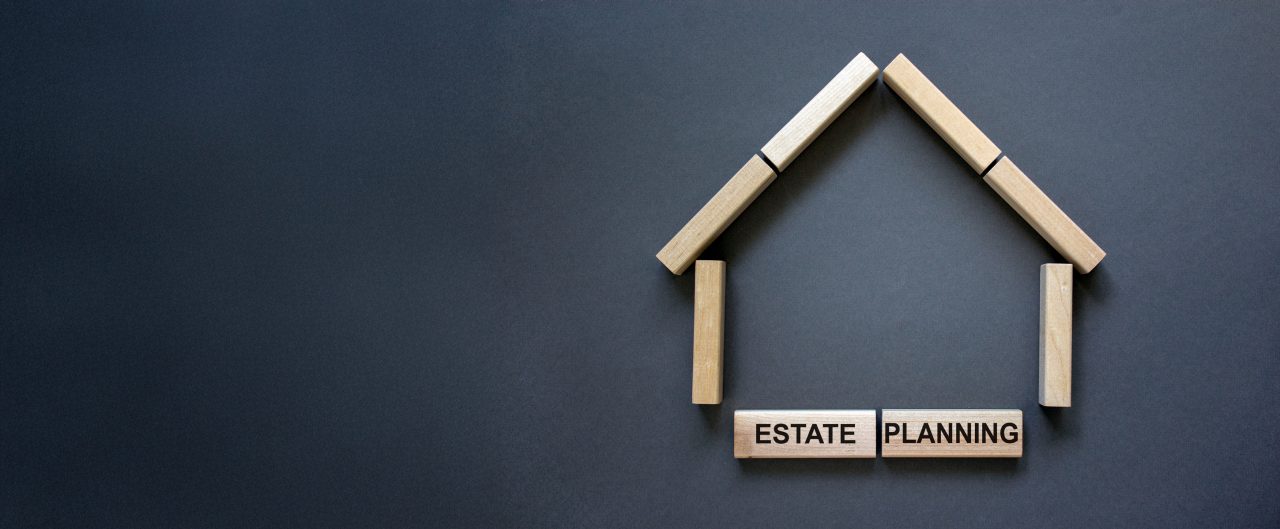 Model of a wooden house from wooden blocks. Words 'estate planning'. Copy space. Business concept. Beautiful grey background.