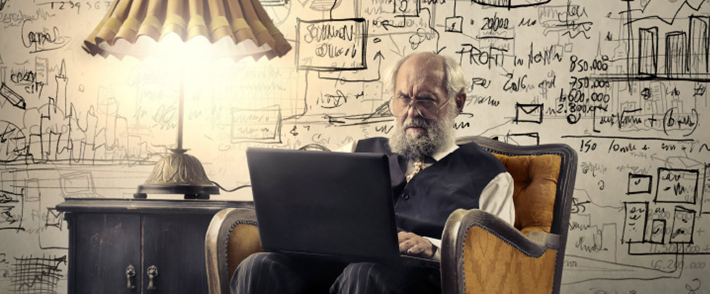 Elderly man sitting in a chair next to a lamp on has laptop